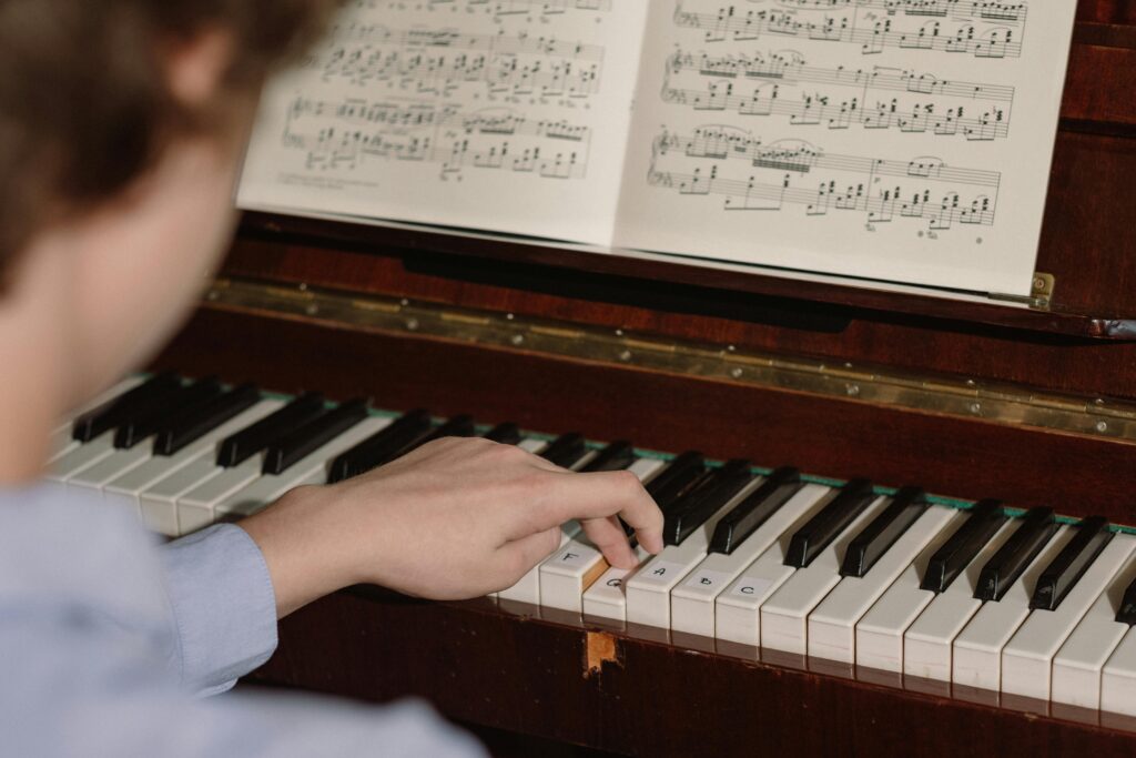 A person playing a piano with a focus on hands and sheet music, highlighting musical practice.